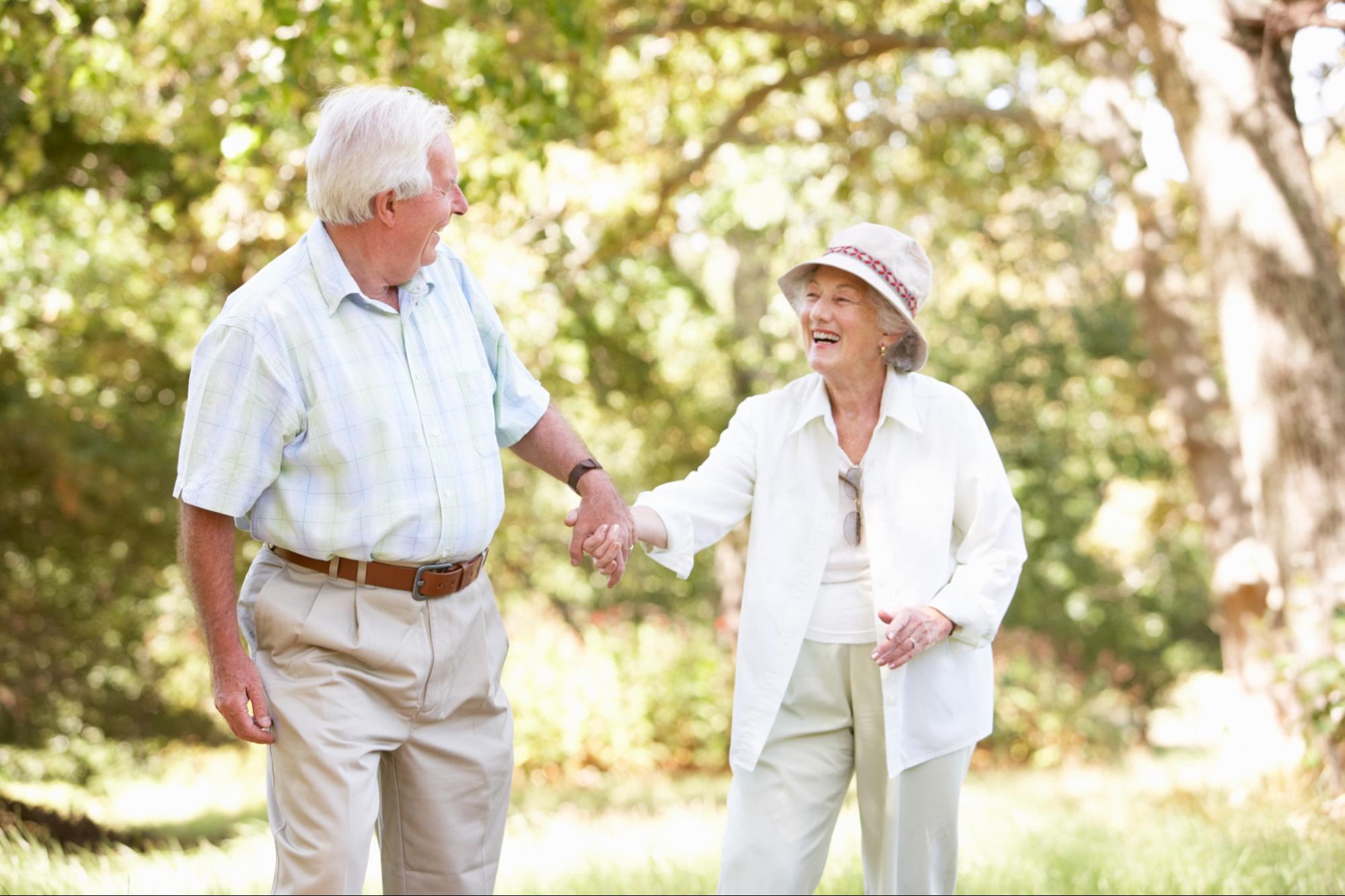 An older adult couple walking together hand-in-hand in a community garden.