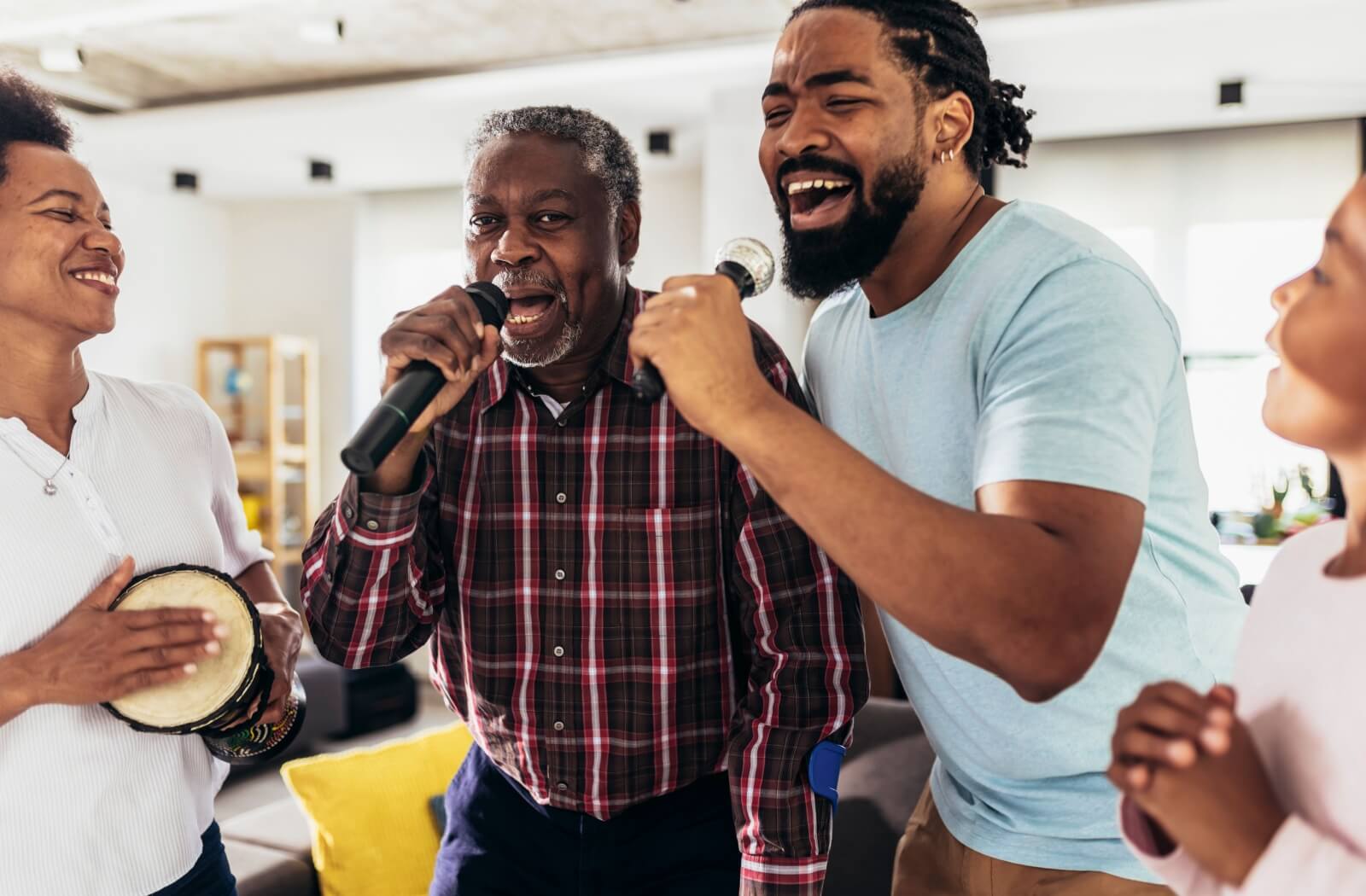 An older adult sings karaoke with their family in their living room, bringing the fun home to a familiar environment
